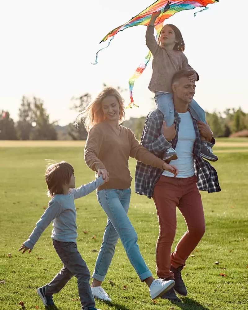 Happy family flying a kite while walking in the park on a sunny day